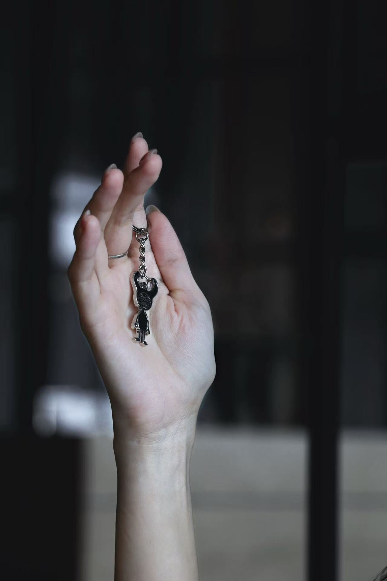 Hand holding a small dark metal character charm against a dim interior.